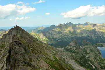Naklejka premium A fragment of a picturesque lake and bizarrely pointed rocks under a cloudy sky on a warm lazy day.