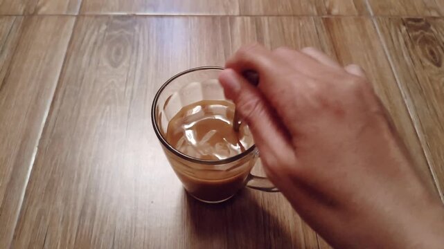 hand is stirring a cup of herbal medicine or Jamu with a spoon.is an Indonesian traditional drink