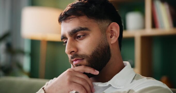Man, thinking and sad in lounge with anxiety from bad memory, conflict or news in home. Indian guy, stress or thoughts in living room with depression, regret and mental health or lonely in apartment