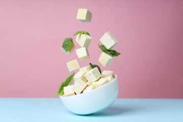 Cubes of tofu in a bowl on a pink background