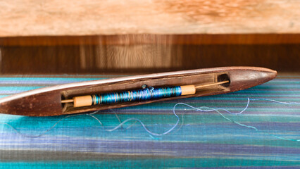 Silk weaving shuttle with blue silk thread on loom