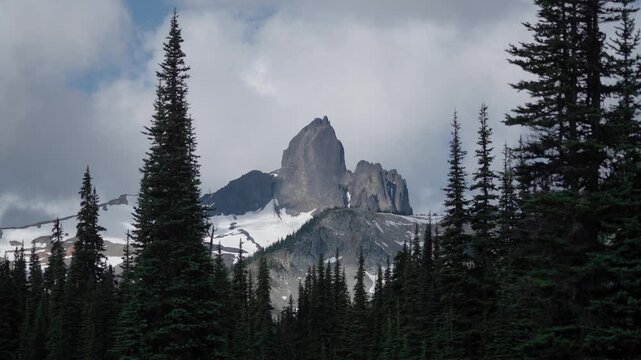 Soft clouds moving quickly over mountain peak in the firest