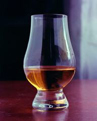 Close up of a snifter of brandy or cognac, backlit, on table
