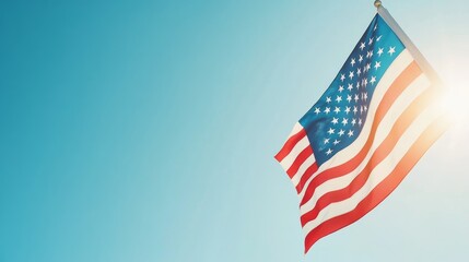 Obraz premium American flag waving proudly, vibrant red, white, and blue stripes against a crystal clear blue sky, with sunlight highlighting its majestic presence