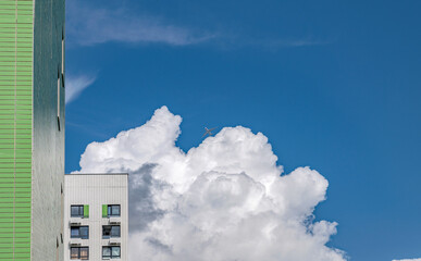 Clouds and an airplane are visible above the houses in the sky