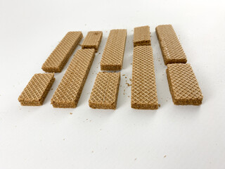 Chocolate wafer biscuits scattered on a white background. Some biscuits are broken into pieces, with crumbs visible. Chocolate wafer biscuits isolated on white background