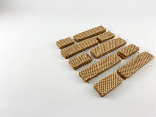 Chocolate wafer biscuits scattered on a white background. Some biscuits are broken into pieces, with crumbs visible. Chocolate wafer biscuits isolated on white background