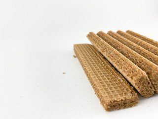 crispy wafer sticks arranged in a staggered pattern on a white background. The wafer sticks have a light brown color and a delicate texture. Wafers with chocolate flavored cream on a white background