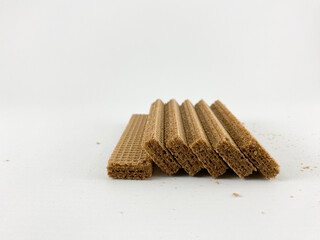 crispy wafer sticks arranged in a staggered pattern on a white background. The wafer sticks have a light brown color and a delicate texture. Wafers with chocolate flavored cream on a white background