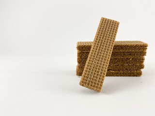 chocolate wafer biscuits arranged on a white background. One biscuit stands upright, leaning against a stack of biscuits.