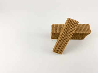 chocolate wafer biscuits arranged on a white background. One biscuit stands upright, leaning against a stack of biscuits.