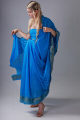 Pretty blonde woman in blue Indian sari on grey background