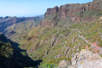 View from the Mirador de Masca showing the twisting narrow road to Masca, TF-436, and the hilltop remote village of Masca in the Teno mountains of the Canary island of Tenerife Spain.	