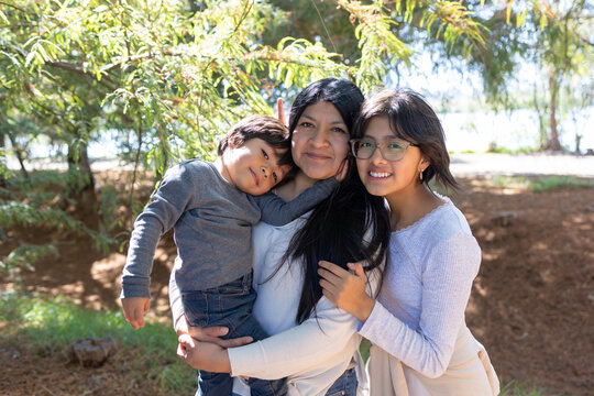 Mexican single mother hugging her children outdoors, mother's day concept 