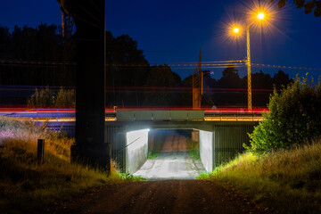 Stockholm, Sweden A small underpass under the E4 highway at night and traffic streaks.