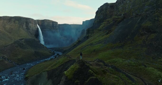 Man Standing On A Rocky Outcrop Gazing At Haifoss Waterfall