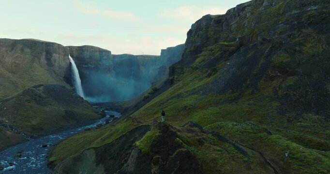 Man Standing On A Mossy Terrain While Viewing Haifoss Waterfall