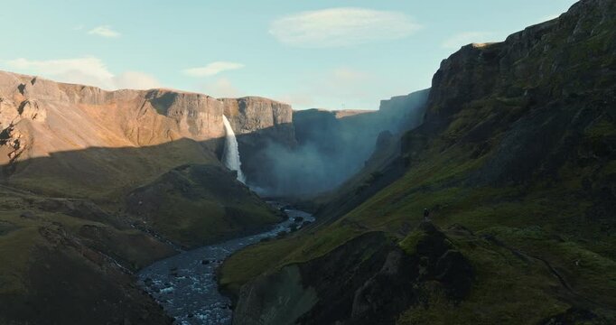 Man Gazing At Haifoss Waterfall From Rocky Outcrop