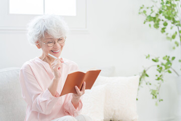 手帳にメモするシニア女性