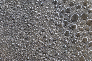 Close-up of numerous water droplets on a metallic surface, showcasing texture, reflection, and patterns