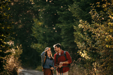A couple with backpacks strolls through the woods, symbolizing the harmony between human connection...
