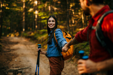Fototapeta premium Happy couple holding hands while hiking together in mountains with backpacks