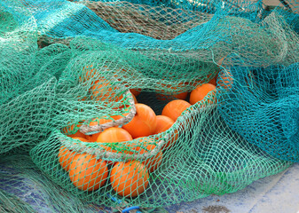 floating orange spheres tied inside a green fishing net used by fishermen during fishing trips in...