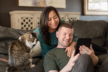 Couple and cat looking at a tablet together