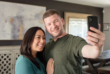 Mixed couple taking a selfie at home