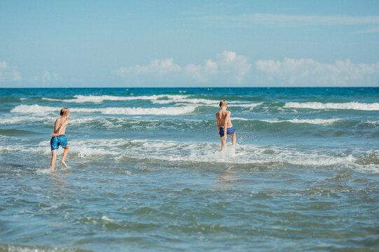 Two brothers playing in ocean waves on a sunny day