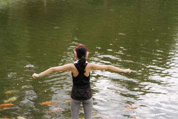 Young attractive Asian woman stretching her arms and legs before her morning exercise run at a running track of a local park