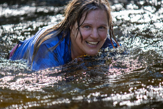 Woman smiling and playing in a creek, enjoying the water and nature