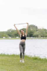 Young woman jogging in the city park Happy brunette female athlete enjoys jogging outdoors. A cute fit woman in a black tracksuit is