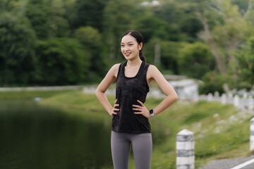 Young attractive Asian woman stretching her arms and legs before her morning exercise run at a running track of a local park