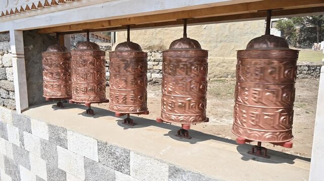 Rows of bronze prayer wheel in Buddhist temple in Kathmandu city of Nepal. The words mantra "Om Mani Padme Hum" is written in Sanskrit on the outside of the wheel.