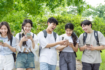 Happy teenagers having fun while using mobile phone in  school