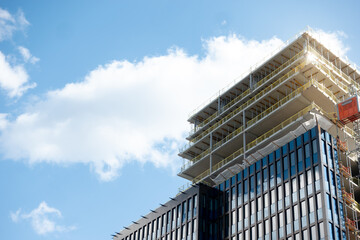 construction site of modern glass facade skyscraper building with a crane against clear sky background, constructing Sickla Central office building