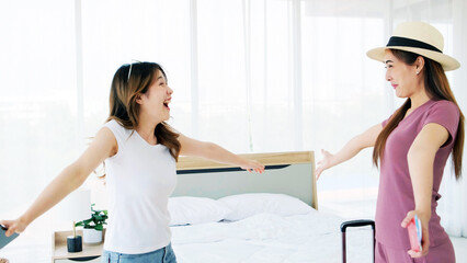 Fototapeta premium A happy young Asian woman hugging a woman carrying luggage from a trip is surprised that her friends have not seen each other for a long time. Expression of girl friendship.