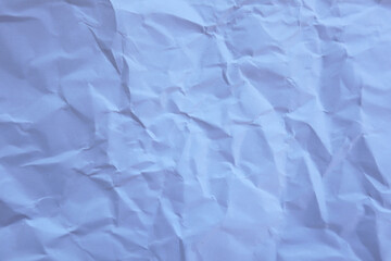 Close-up of crumpled paper. Light blue creases and folds create a textured surface with natural shadows and depth