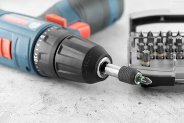 Professional cordless drill screwdriver and screwdriver bit set close-up. Quick-change universal holder with locking mechanism to ensure a secure hold and fast bits changes, emphasis on detail.