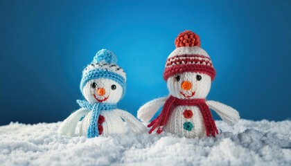 Obraz premium little knitted snowmans on soft snow on blue background