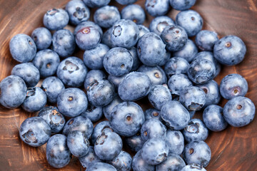 Fresh juicy organic blueberries in an eco-friendly wooden bowl close-up