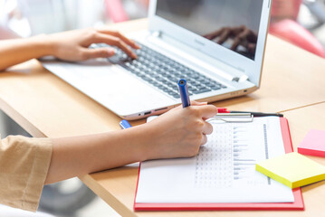 Women Freelance work on computer pointing with color pen electronic gadgets dropped around on table