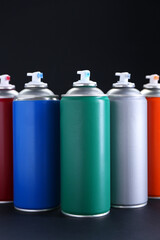 Many spray paint cans on dark gray background