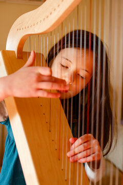 A little girl plays harp in patch of sunlight