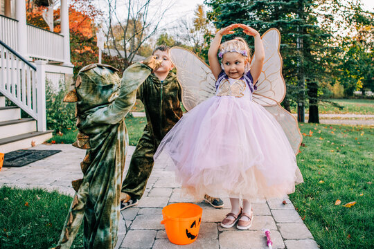 Kids in fairy and dragon costumes, trick-or-treating on Halloween