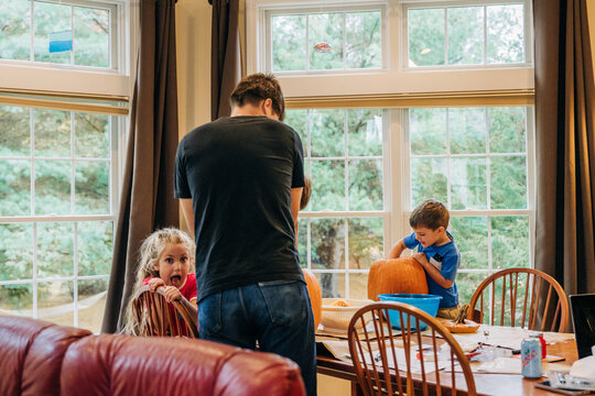 Family carving pumpkins indoors, kids and father activity