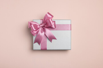 Beautiful gift box with pink bow on beige background, top view