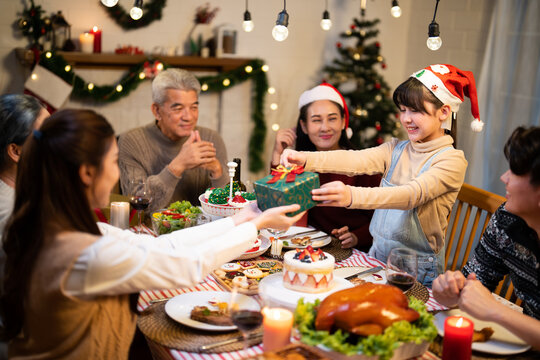 Asian family joyful gathers around the Christmas in July dinner table exchanging gifts and reunion celebrating the summer holiday season together