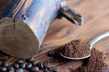 Ground and bean coffee in a wooden spoon close-up on a wooden board